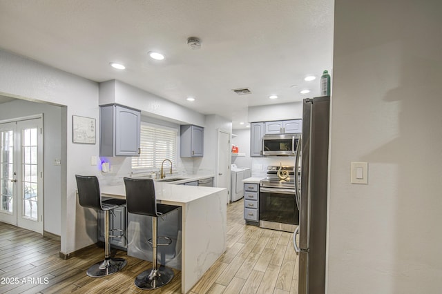 4162 W Sierra St, Phoenix, AZ 85029 - kitchen with stainless steel appliances, washer and dryer, a peninsula, gray cabinetry, and light wood-style flooring