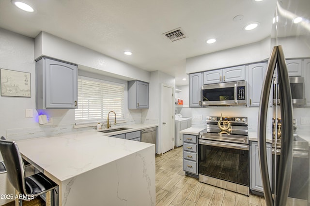 4162 W Sierra St, Phoenix, AZ 85029 - kitchen with stainless steel appliances, washer and clothes dryer, gray cabinetry, a peninsula, and a sink