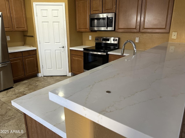 7511 S 45th Dr, Laveen, AZ 85339 - kitchen featuring light stone counters, appliances with stainless steel finishes, and a peninsula