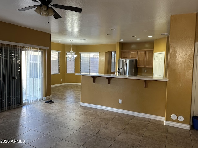 7511 S 45th Dr, Laveen, AZ 85339 - kitchen featuring ceiling fan with notable chandelier, a kitchen breakfast bar, a peninsula, stainless steel fridge with ice dispenser, and light countertops