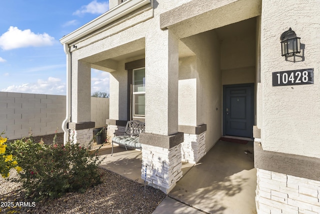 property entrance with fence and stucco siding