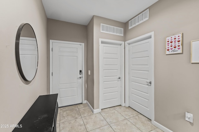 foyer featuring light tile patterned floors, baseboards, and visible vents