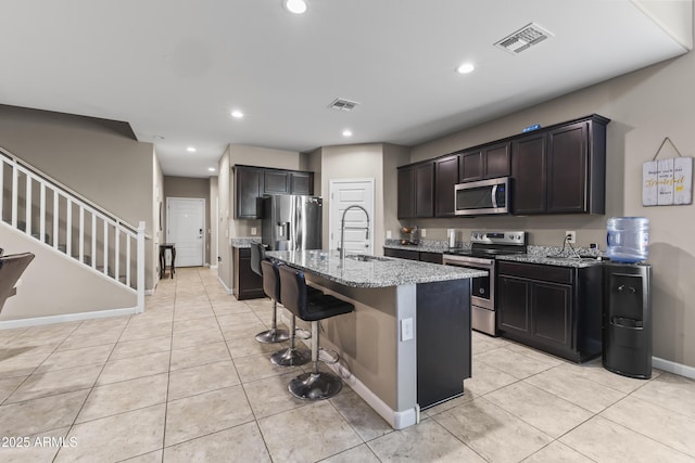 kitchen with visible vents, appliances with stainless steel finishes, a sink, and a center island with sink