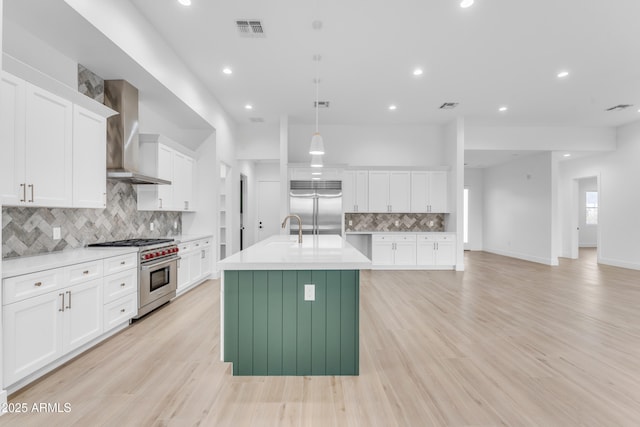 kitchen with wall chimney exhaust hood, pendant lighting, high quality appliances, and white cabinets