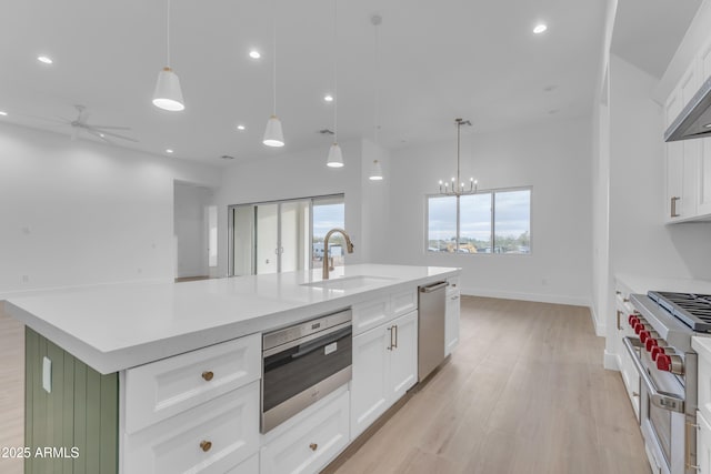 kitchen with sink, a center island with sink, white cabinets, and decorative light fixtures