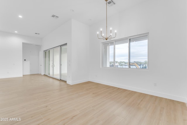 unfurnished room with a chandelier and light hardwood / wood-style flooring