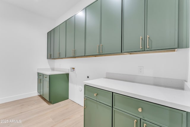 washroom with cabinets, hookup for a washing machine, hookup for an electric dryer, and light wood-type flooring