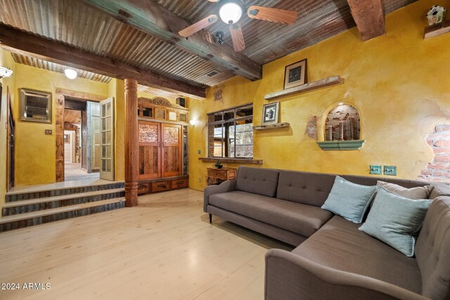 living room featuring light wood-type flooring, decorative columns, ceiling fan, beam ceiling, and wooden ceiling