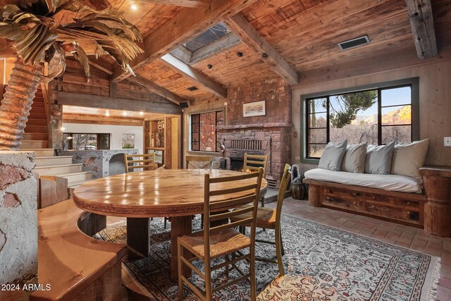 dining space with vaulted ceiling with beams, a fireplace, and wooden ceiling