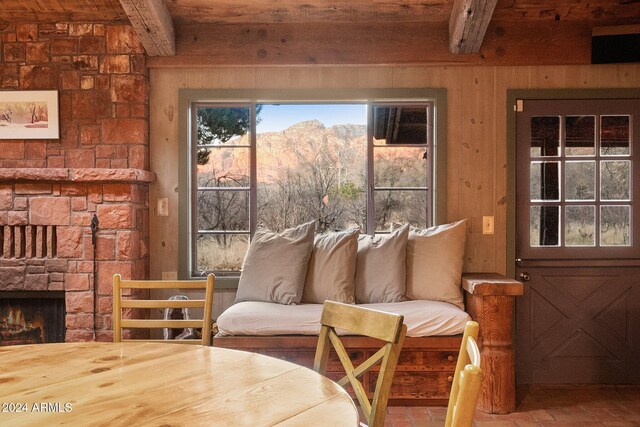 sunroom / solarium with a mountain view, a stone fireplace, and beamed ceiling