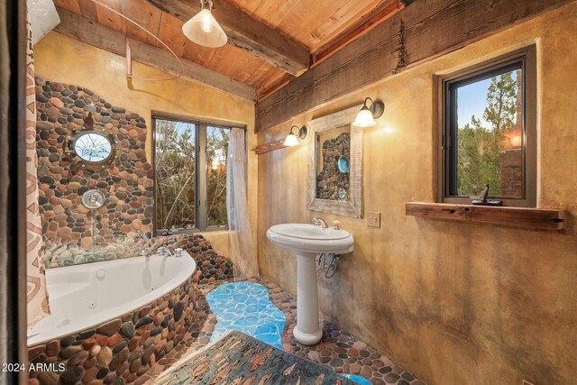 bathroom featuring beam ceiling, wood ceiling, a bath, and a wealth of natural light