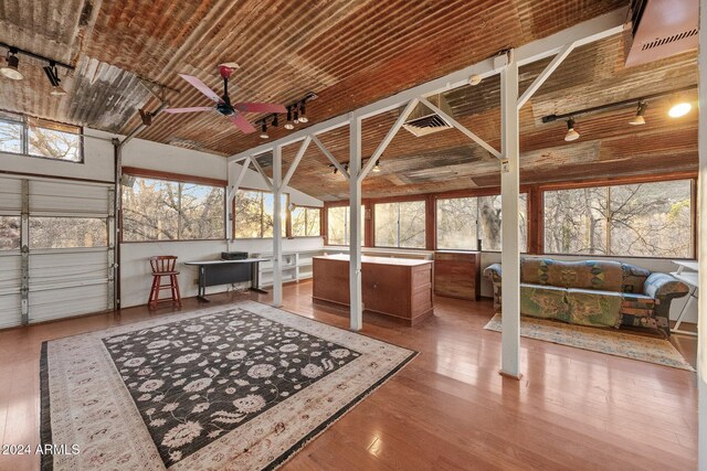 sunroom / solarium featuring rail lighting, ceiling fan, a healthy amount of sunlight, and brick ceiling