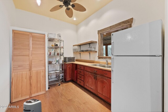 kitchen with light wood-type flooring, white fridge, ceiling fan, and sink