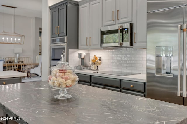 kitchen with light stone countertops, tasteful backsplash, stainless steel appliances, a center island, and gray cabinets