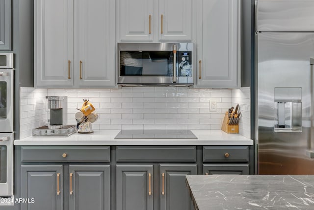 kitchen with gray cabinets, appliances with stainless steel finishes, and tasteful backsplash