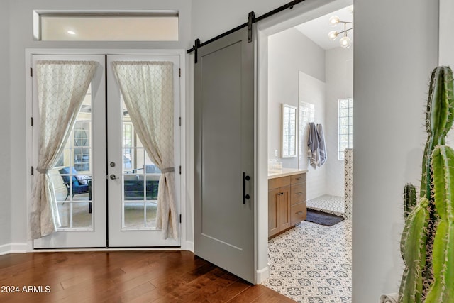 doorway with french doors, a barn door, dark hardwood / wood-style floors, and a healthy amount of sunlight