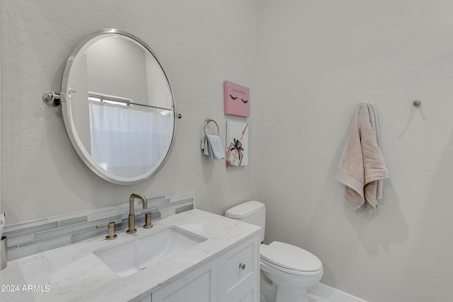 bathroom with vanity, toilet, and tasteful backsplash