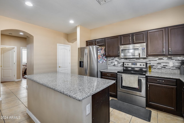 kitchen featuring backsplash, light stone counters, a center island, and stainless steel appliances