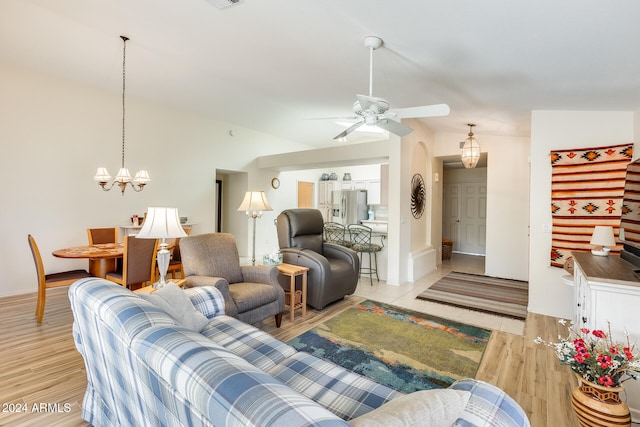 living room featuring ceiling fan with notable chandelier and light hardwood / wood-style flooring