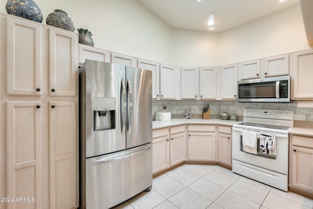 kitchen with decorative backsplash, a towering ceiling, light tile patterned flooring, and appliances with stainless steel finishes