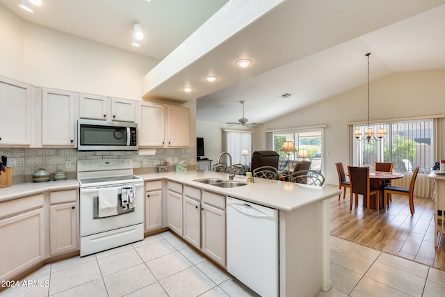 kitchen with kitchen peninsula, white appliances, sink, pendant lighting, and lofted ceiling