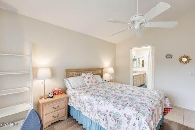 bedroom featuring ceiling fan, ensuite bathroom, lofted ceiling, and light wood-type flooring