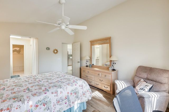 bedroom featuring ceiling fan, light hardwood / wood-style floors, lofted ceiling, and connected bathroom