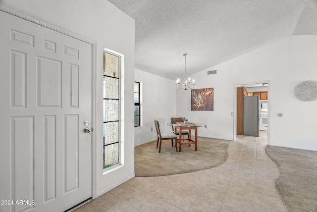 tiled foyer entrance featuring a textured ceiling, lofted ceiling, and a notable chandelier