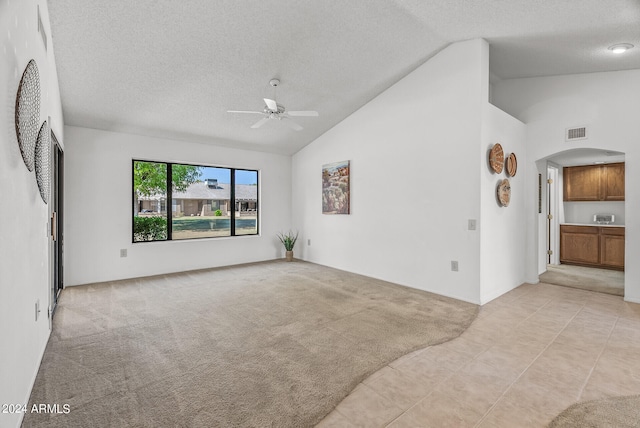 unfurnished living room featuring light carpet, ceiling fan, and a textured ceiling