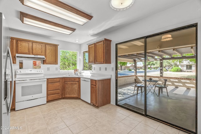 kitchen with sink, light tile patterned floors, and white appliances