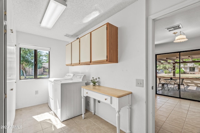 laundry room featuring washing machine and dryer, light tile patterned flooring, cabinets, and a textured ceiling