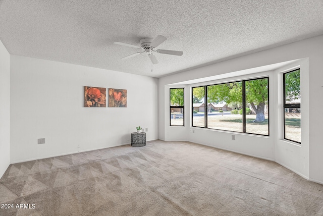 empty room featuring ceiling fan, light colored carpet, and a textured ceiling