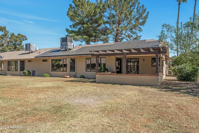 back of property with a lawn, central AC, and solar panels