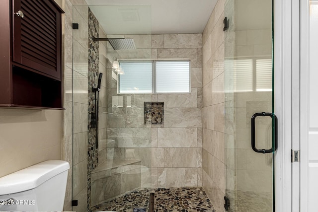 bathroom featuring toilet and a shower with shower door