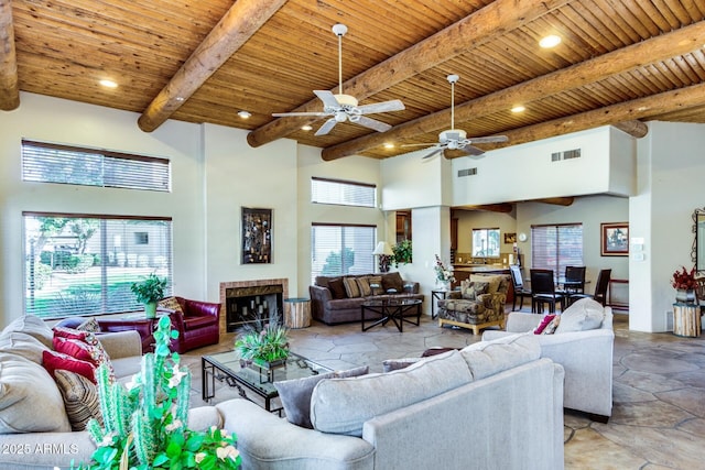 living room with a tiled fireplace, a high ceiling, wooden ceiling, and beam ceiling