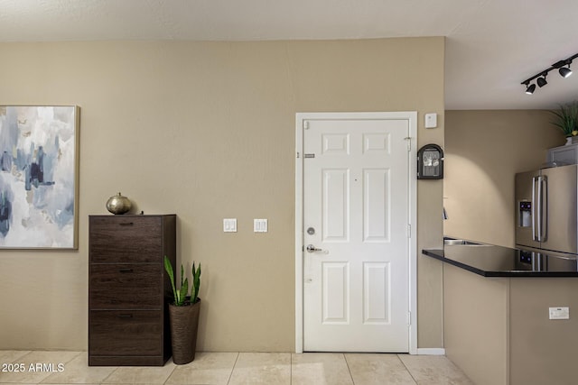 entryway with rail lighting and light tile patterned flooring