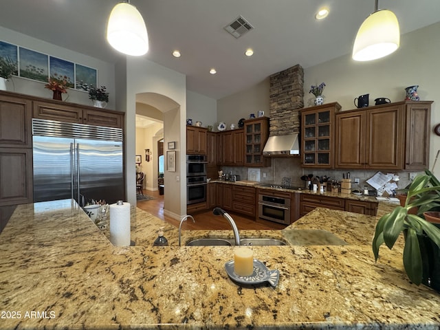 kitchen featuring sink, tasteful backsplash, hanging light fixtures, appliances with stainless steel finishes, and exhaust hood