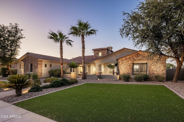 view of front of property with stone siding, a front lawn, a tiled roof, and stucco siding