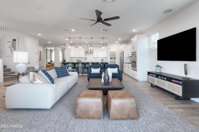 living area featuring recessed lighting, wood finished floors, visible vents, a ceiling fan, and stairway