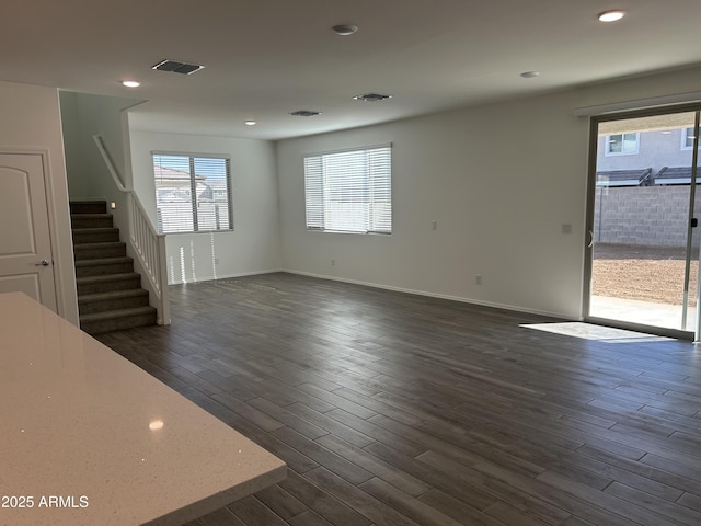 unfurnished living room featuring baseboards, visible vents, stairway, dark wood-style flooring, and recessed lighting