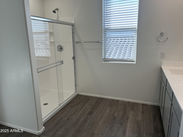 full bath featuring vanity, a shower stall, baseboards, and wood finished floors