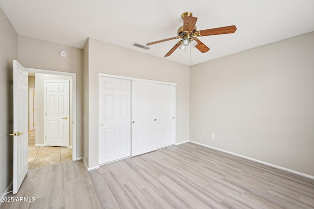 unfurnished bedroom with light wood-type flooring, visible vents, a closet, baseboards, and ceiling fan