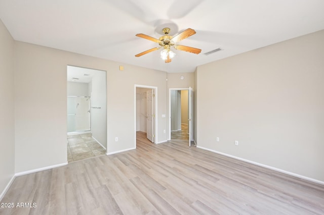 unfurnished bedroom with ensuite bath, a closet, light wood-style floors, baseboards, and a spacious closet