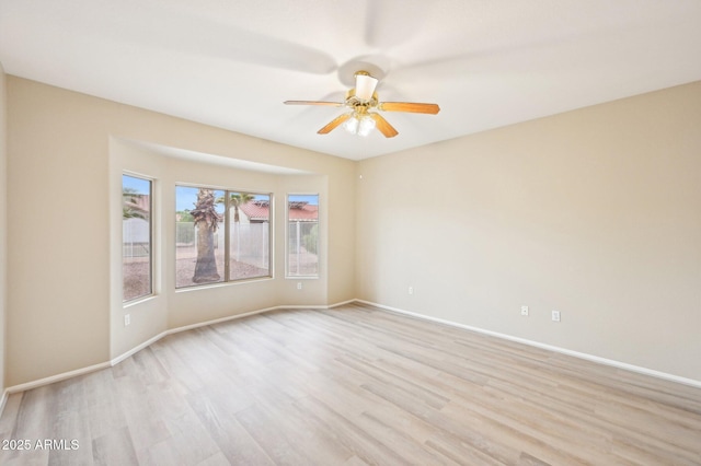 empty room featuring baseboards, ceiling fan, and light wood finished floors