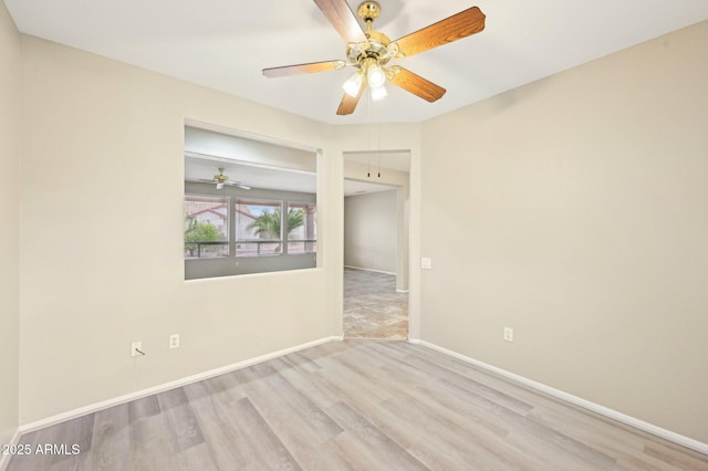 spare room featuring baseboards, wood finished floors, and a ceiling fan