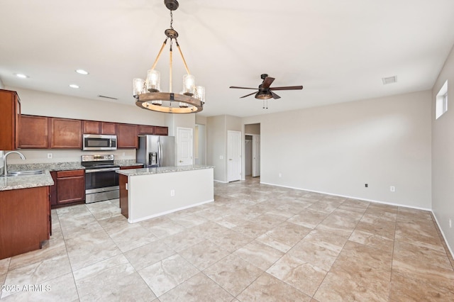 kitchen with a sink, appliances with stainless steel finishes, ceiling fan with notable chandelier, open floor plan, and a center island