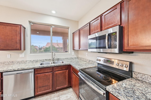 kitchen with a sink, stainless steel appliances, light stone counters, and recessed lighting