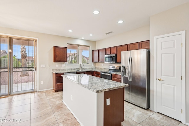 kitchen featuring a wealth of natural light, a kitchen island, stainless steel appliances, and a sink