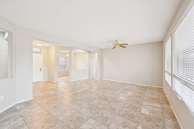 empty room with a healthy amount of sunlight, baseboards, and ceiling fan