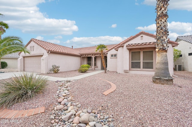 mediterranean / spanish home with concrete driveway, a tile roof, central AC unit, stucco siding, and a garage